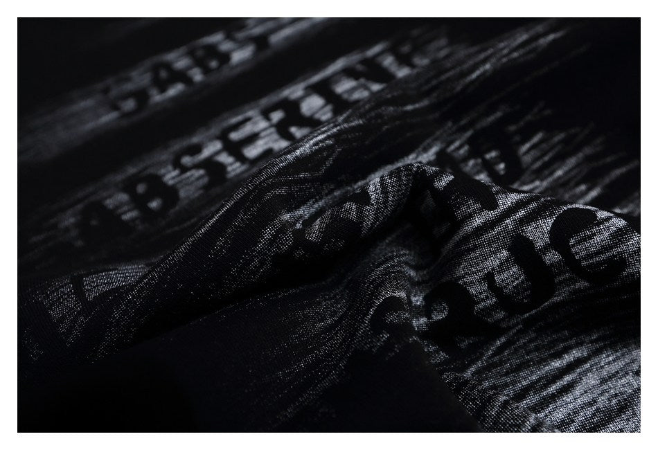 Macro view of black printed fabric gathered into folds, showing distressed gray English lettering.