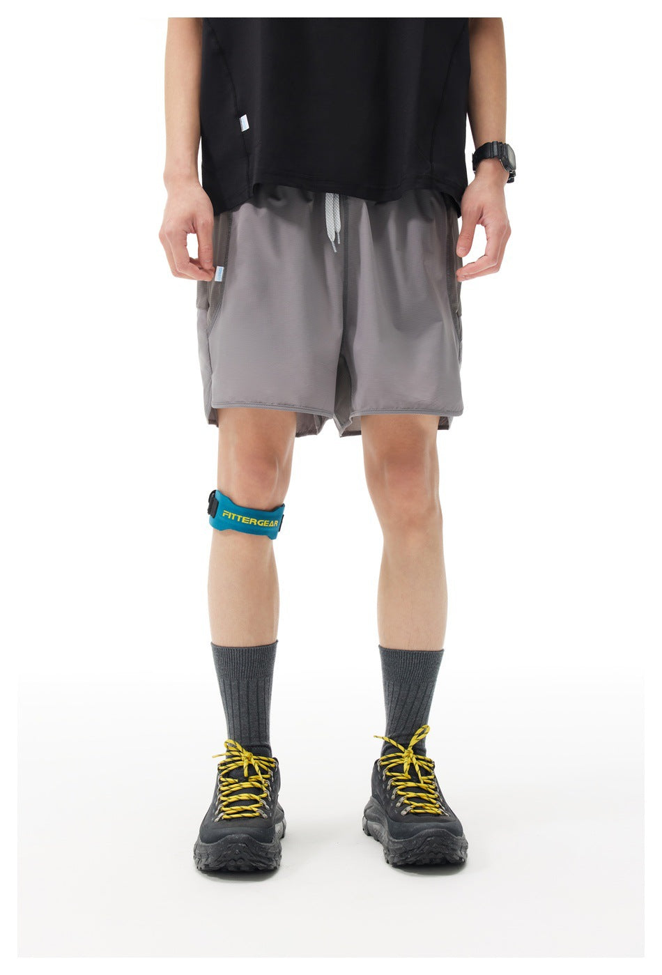 Front view of a model wearing loose gray shorts with a drawstring waist and layered hems.