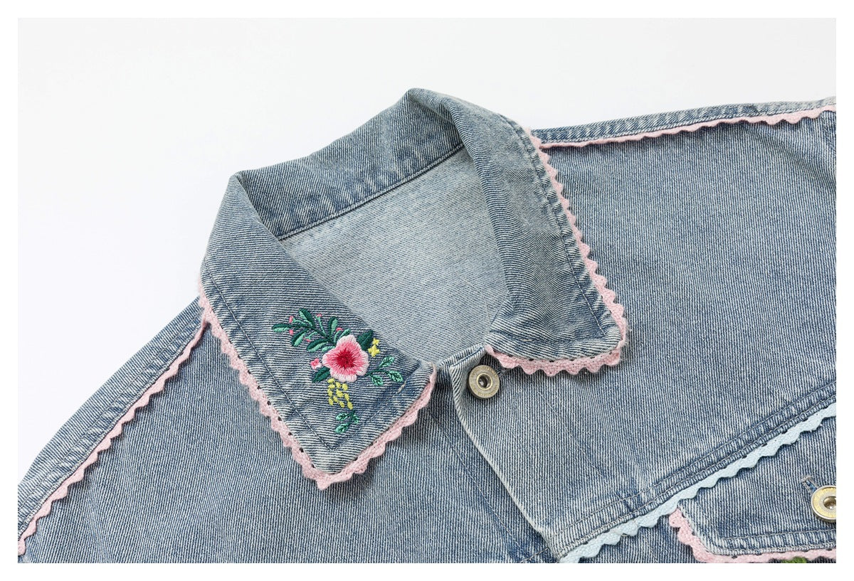 Close-up of a blue denim jacket collar with pink scalloped trim and floral embroidery.