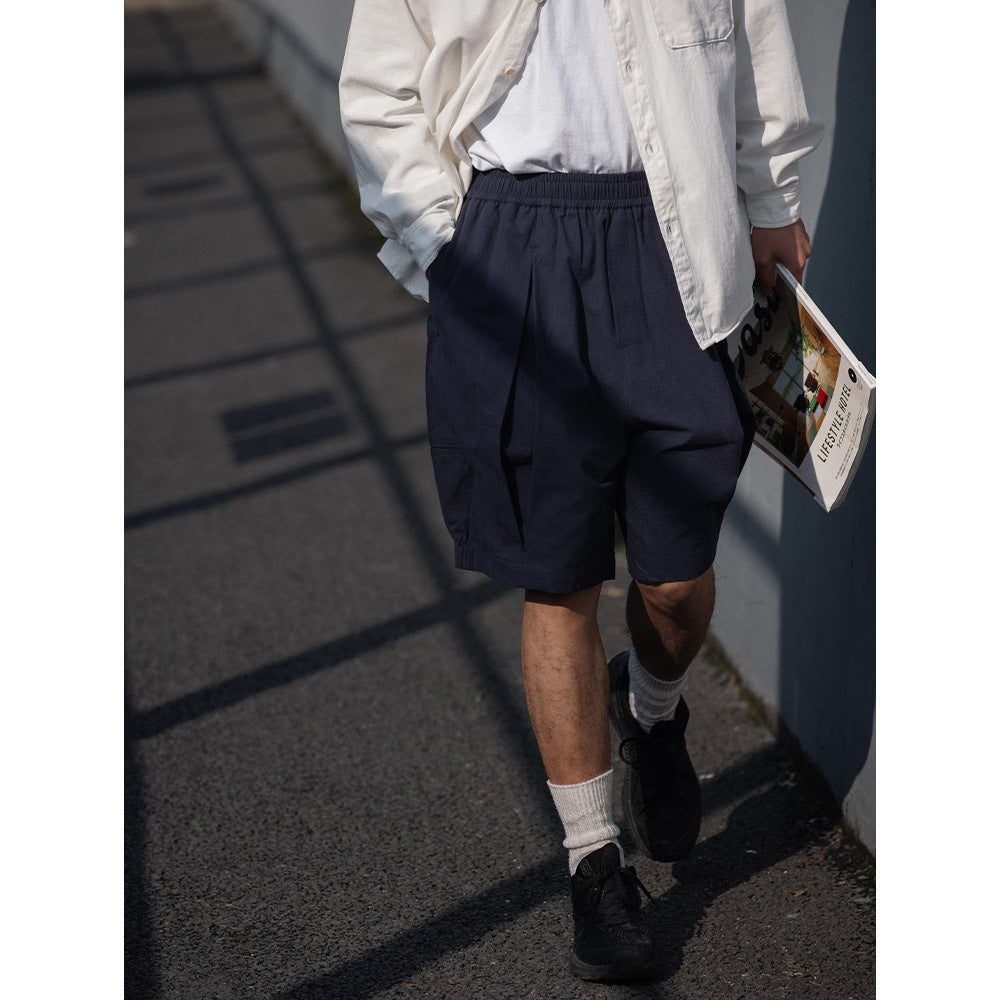 Cropped street-style view of a person wearing loose navy shorts with an elastic waist and white shirt.