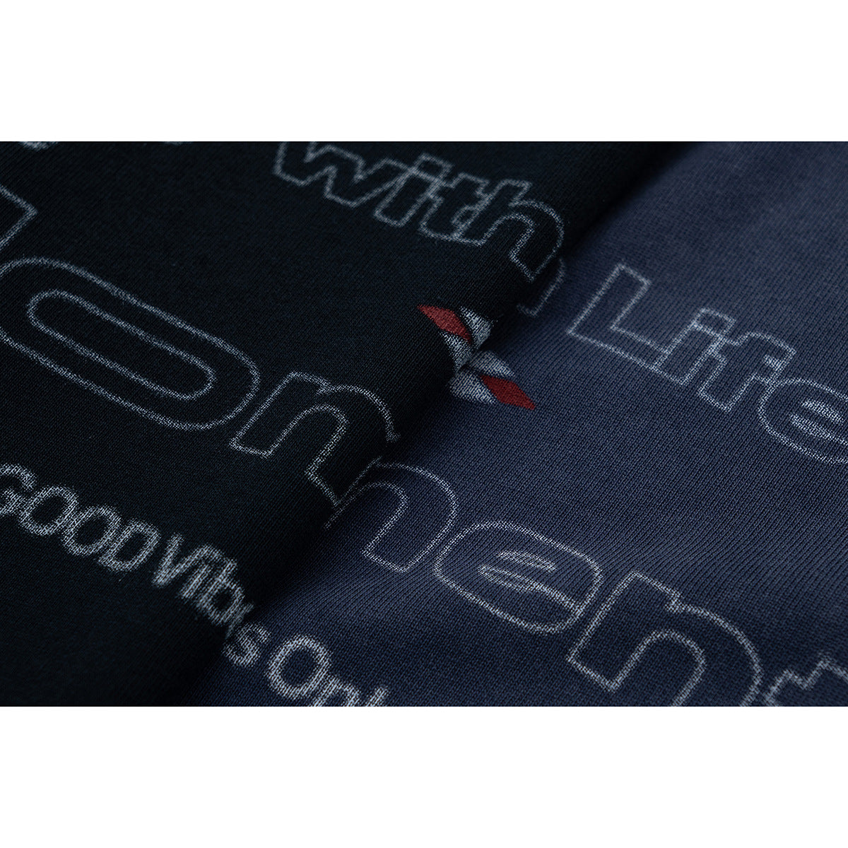 Close-up of the T-shirt's pale outlined lettering and small red-and-white graphic on dark fabric.