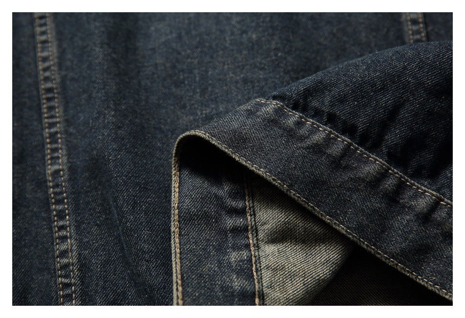 Close-up of dark indigo denim showing a folded edge, inner fabric, and tan stitching.