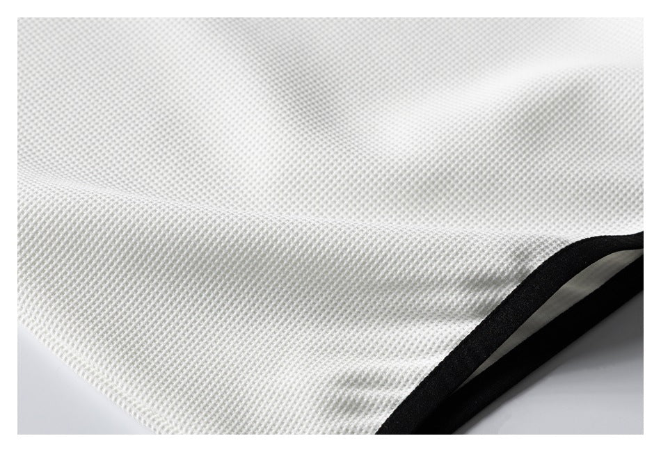 Close-up of white waffle-textured fabric with a curved black bound edge.