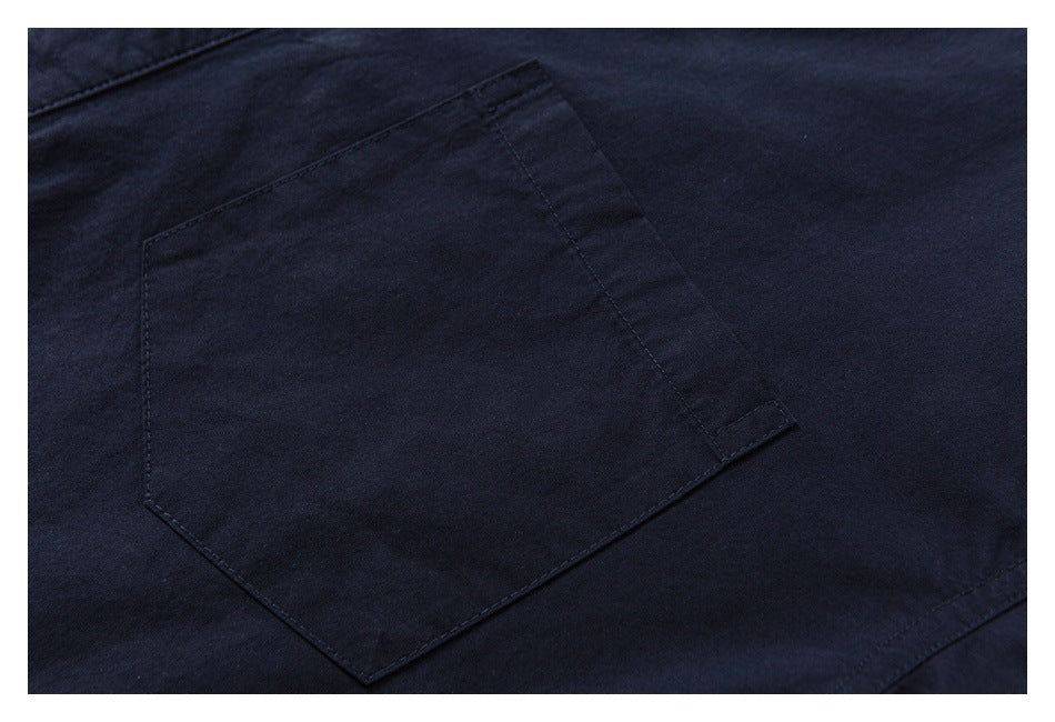 Close-up of a dark navy shirt's angular patch pocket and stitching.