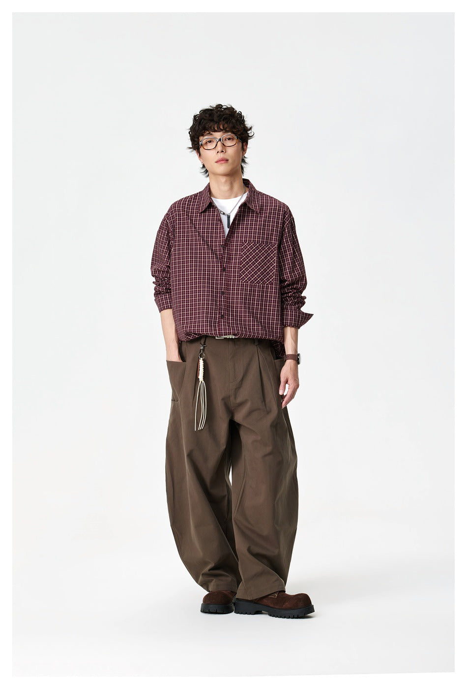Full-length view of a model in the dark red check shirt with a white tee, brown wide-leg pants and dark shoes