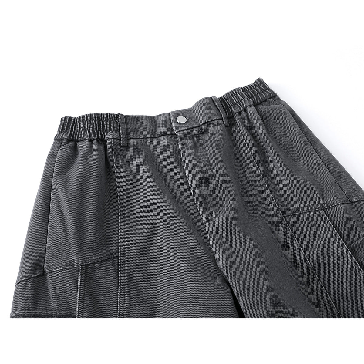 Close-up of charcoal wide-leg cargo pants showing the elasticated waistband, button closure and panel seams.