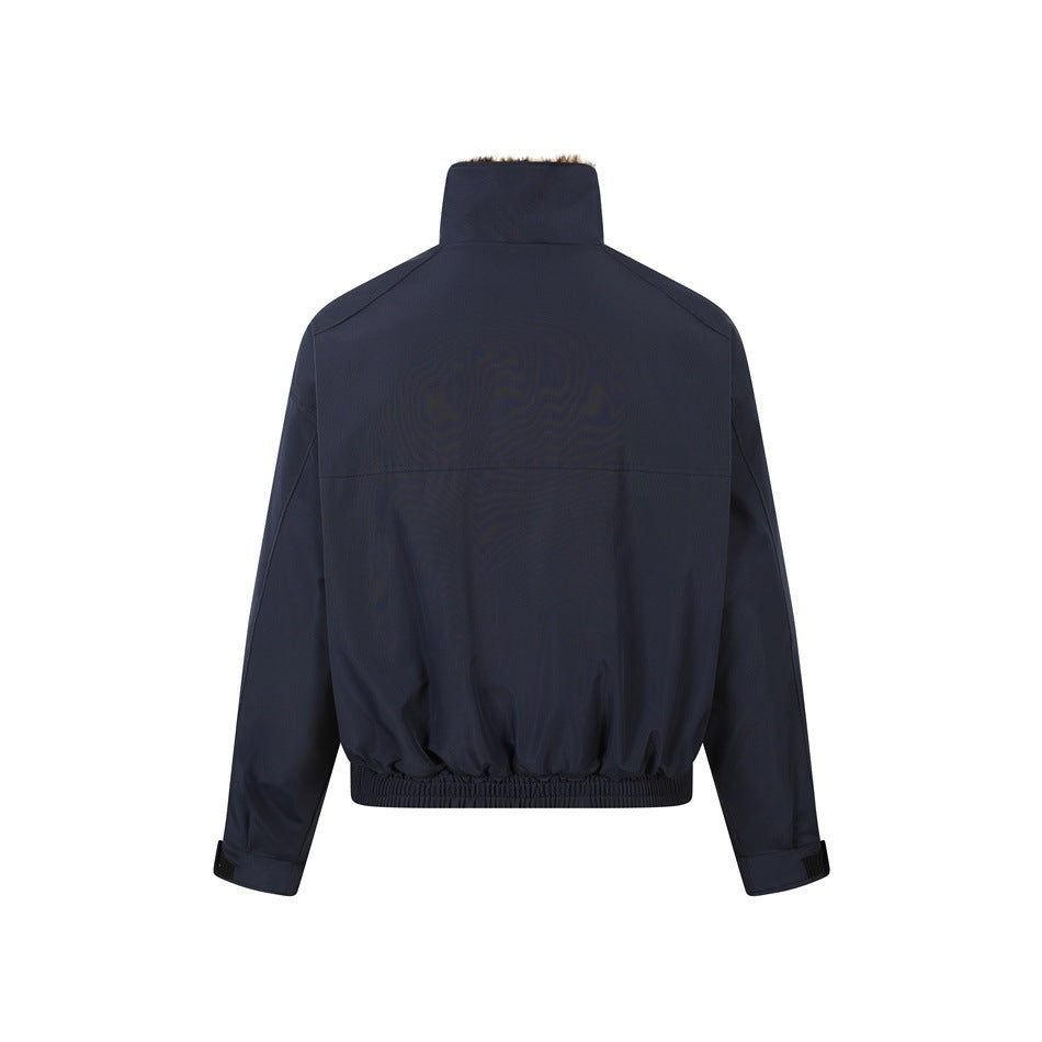Back view of a dark navy jacket with a high collar, long sleeves, adjustable cuffs, and an elasticized hem.