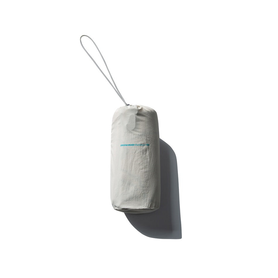 Off-white drawstring stuff sack with a long cord loop and small teal branding, isolated against white.
