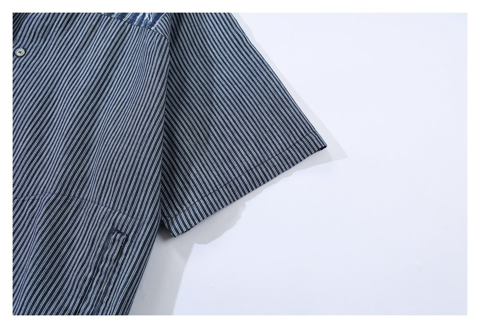 Partial view of a short-sleeve navy pinstripe shirt, showing a button, sleeve, and pocket edge.