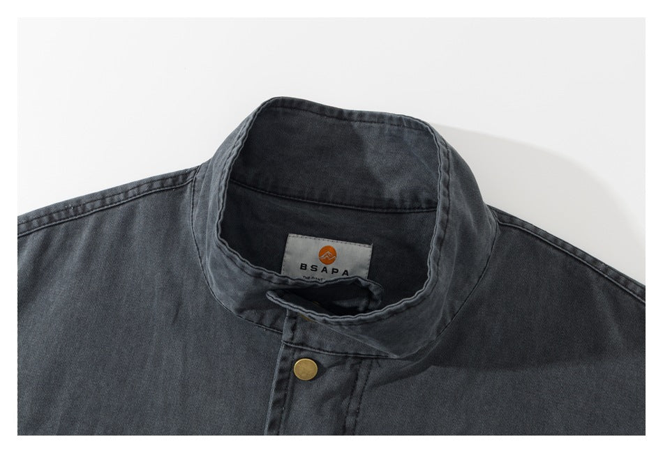 Close-up of a charcoal jacket's stand collar, brass snap, and inner brand label.