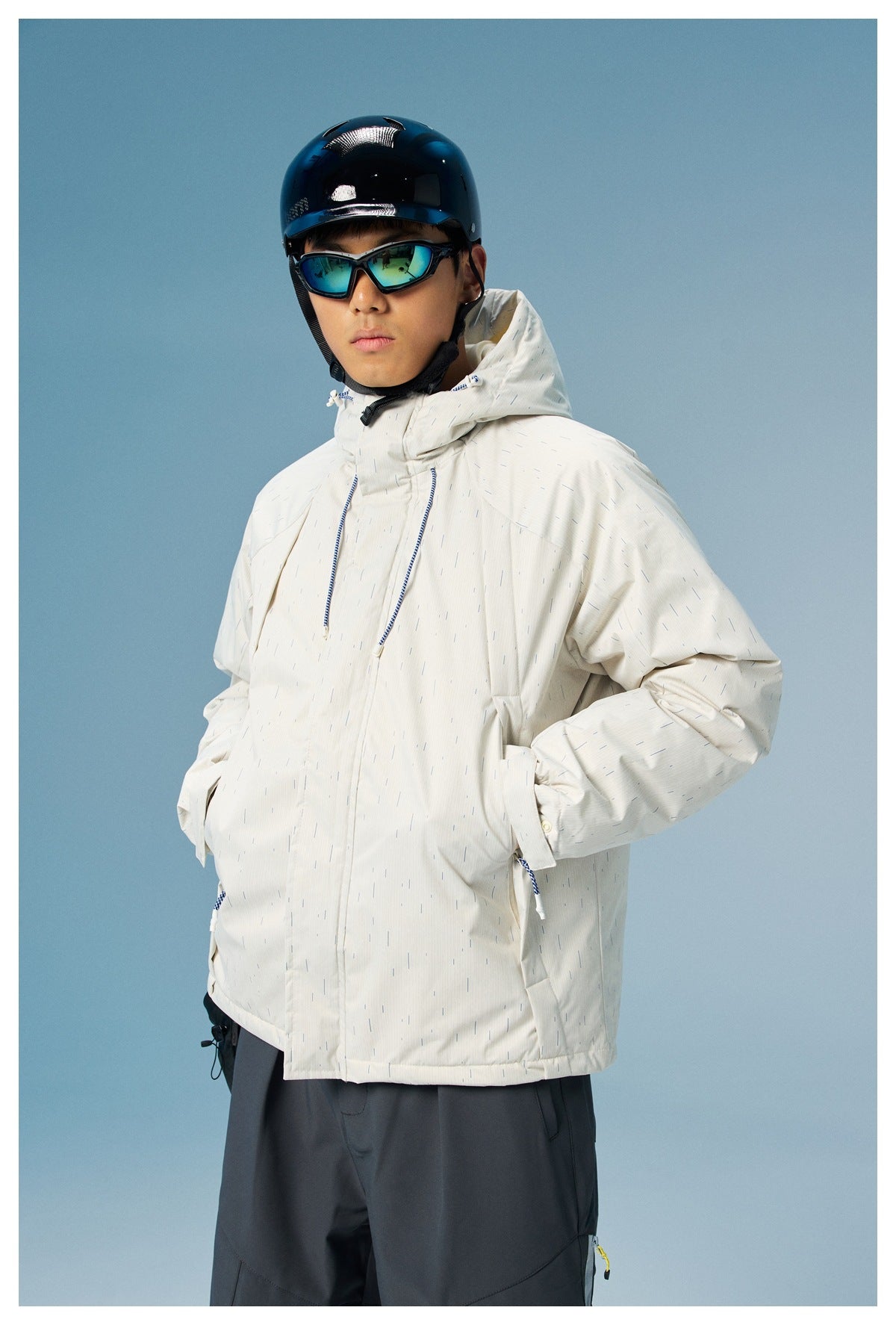 Model wearing a white hooded jacket with fine blue dash pattern and dark pants, shown from the front.