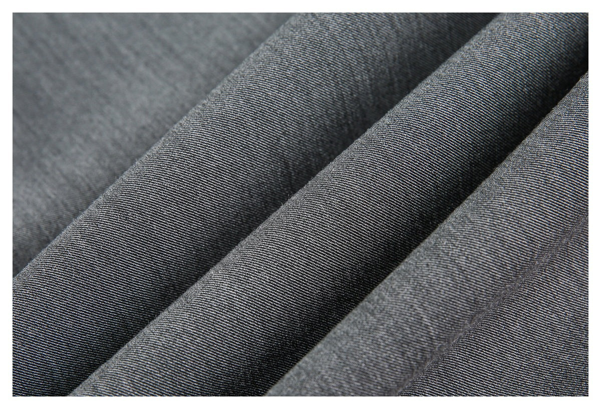 Macro close-up of the fine diagonal weave and folds of charcoal-gray trouser fabric.