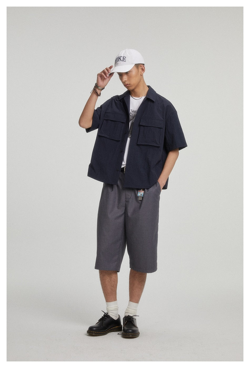 Front view of a model wearing a dark navy short-sleeve overshirt with two flap pockets and charcoal shorts.