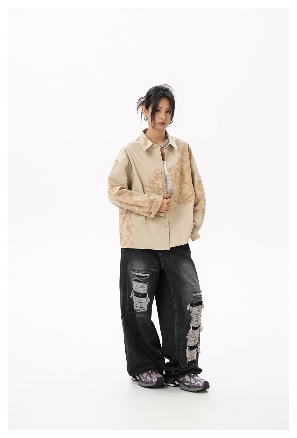 Full-length model wearing a beige shirt with tan textured panels and wide ripped black jeans.