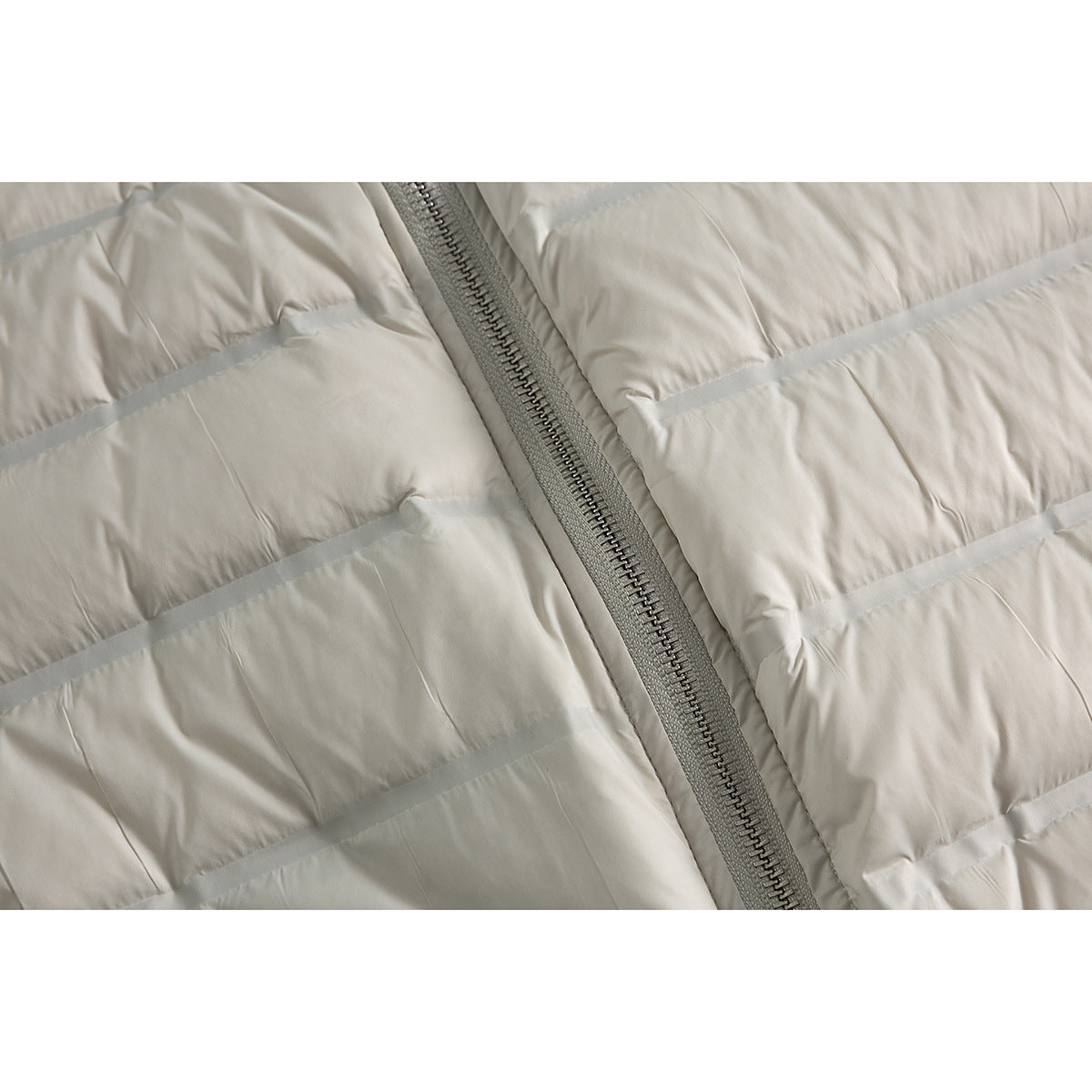 Close-up of a light gray quilted jacket showing horizontal channels and its central zipper.