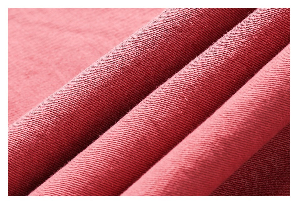 Macro view of dusty rose fabric folded into ridges, showing its fine diagonal weave.