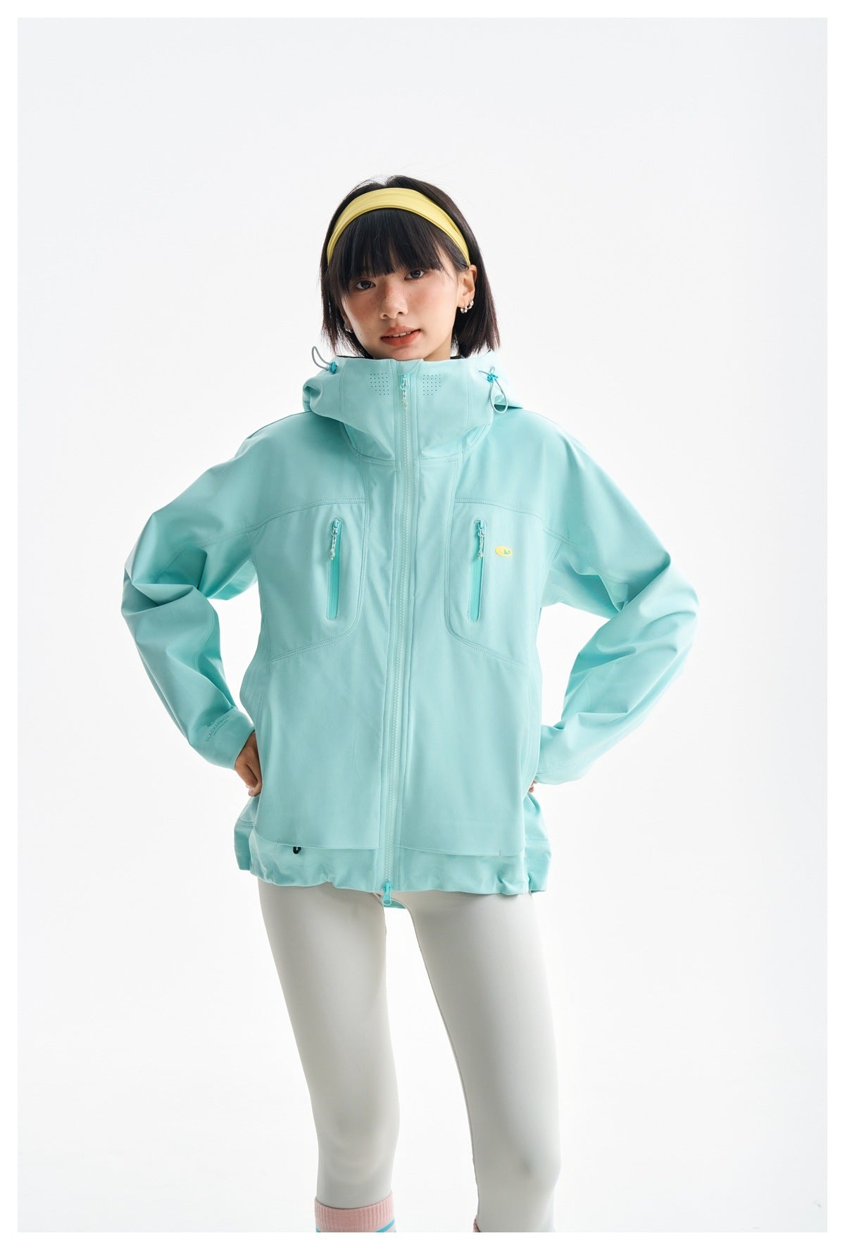 Front view of a model wearing an aqua hooded jacket with a full-length zip and two vertical chest pockets.