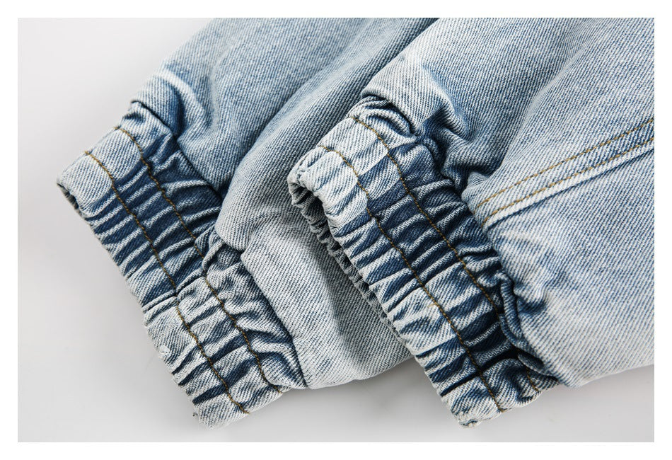 Close-up of a gathered light-wash denim cuff with tan stitching.