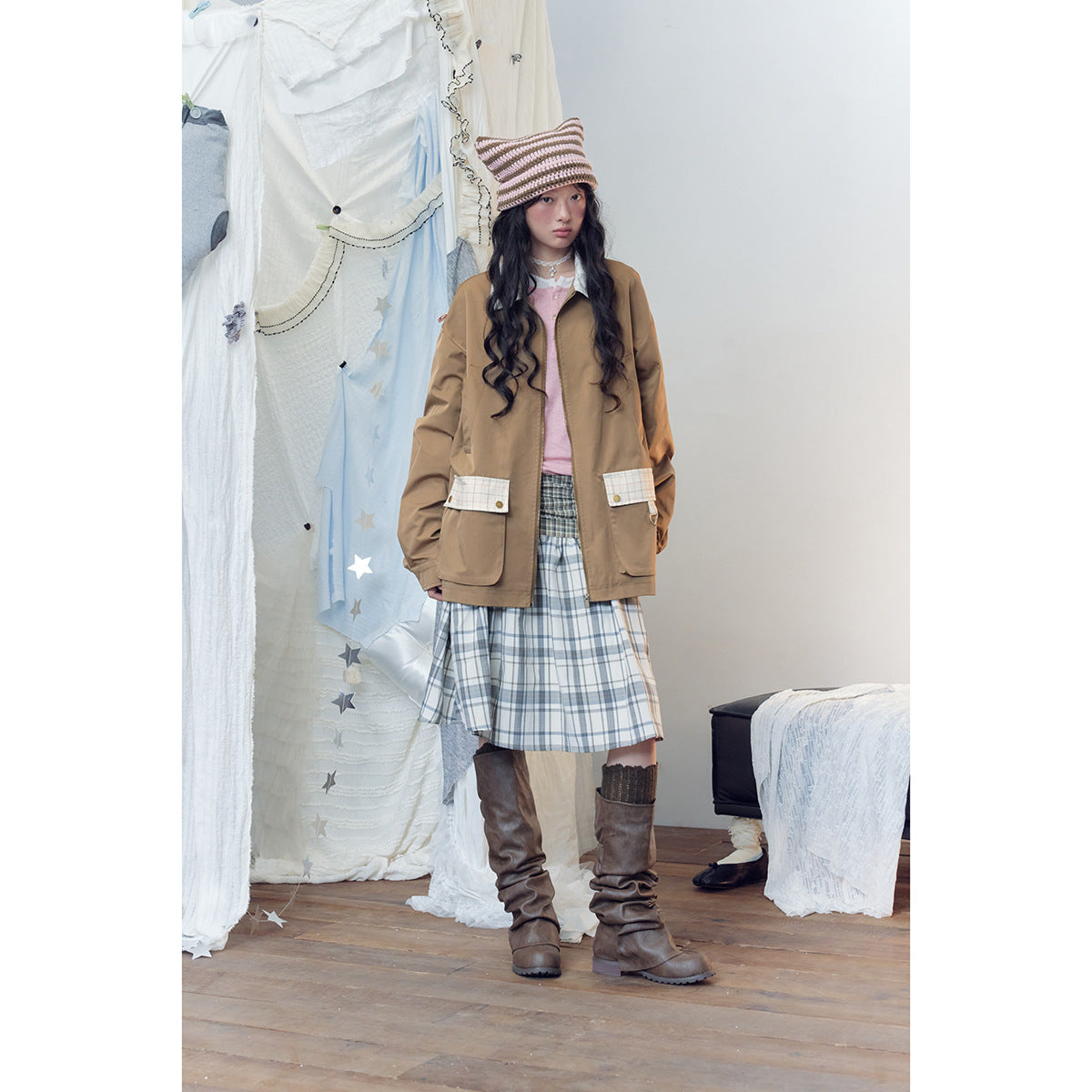 Full-length view of a model wearing a brown jacket with plaid pocket flaps and a blue-gray plaid skirt.