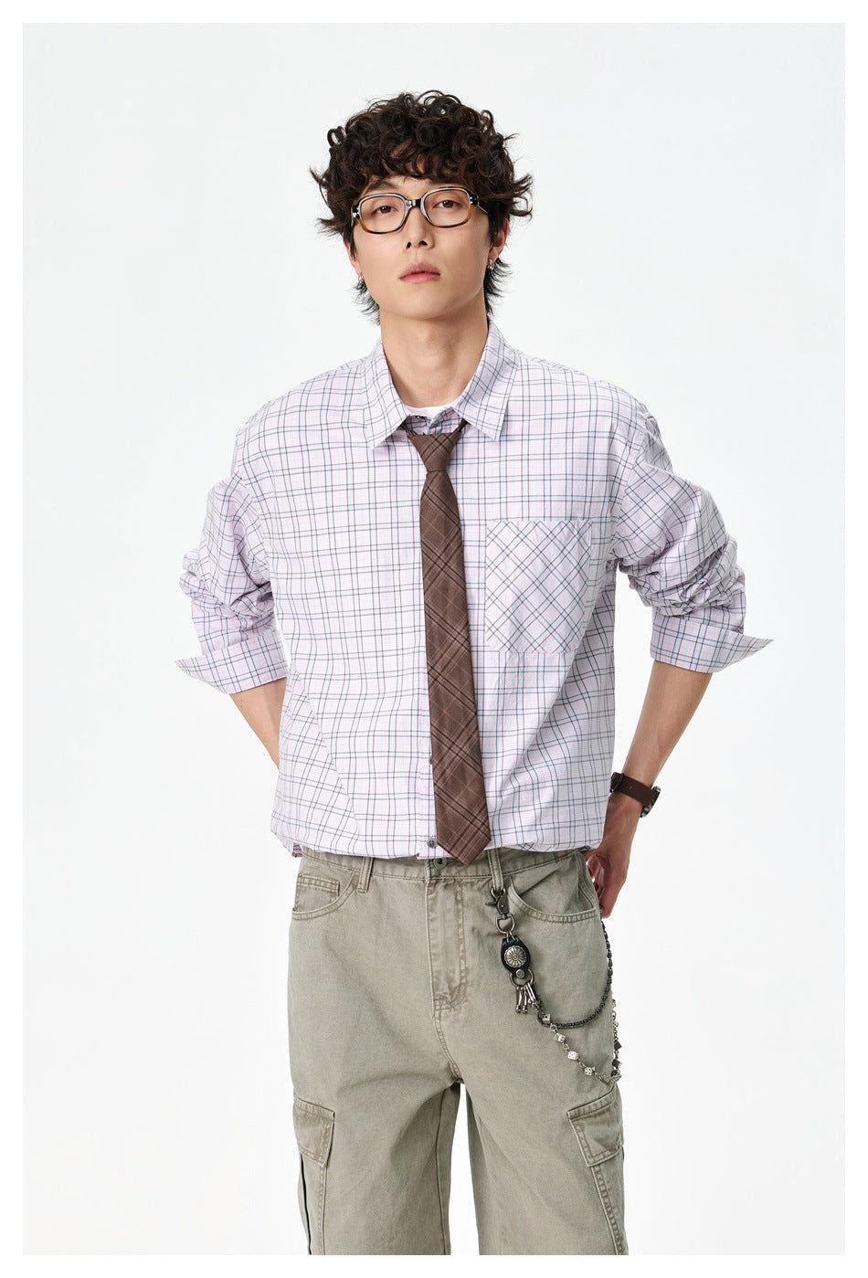 Man wearing a pink check button-up shirt with sleeves pushed up, brown tie and olive cargo pants, front view