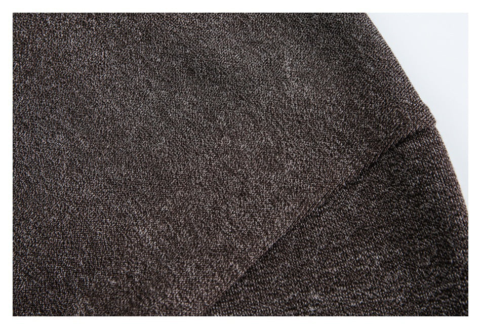 Close-up of a seam and folded edge on dark brown textured garment fabric.