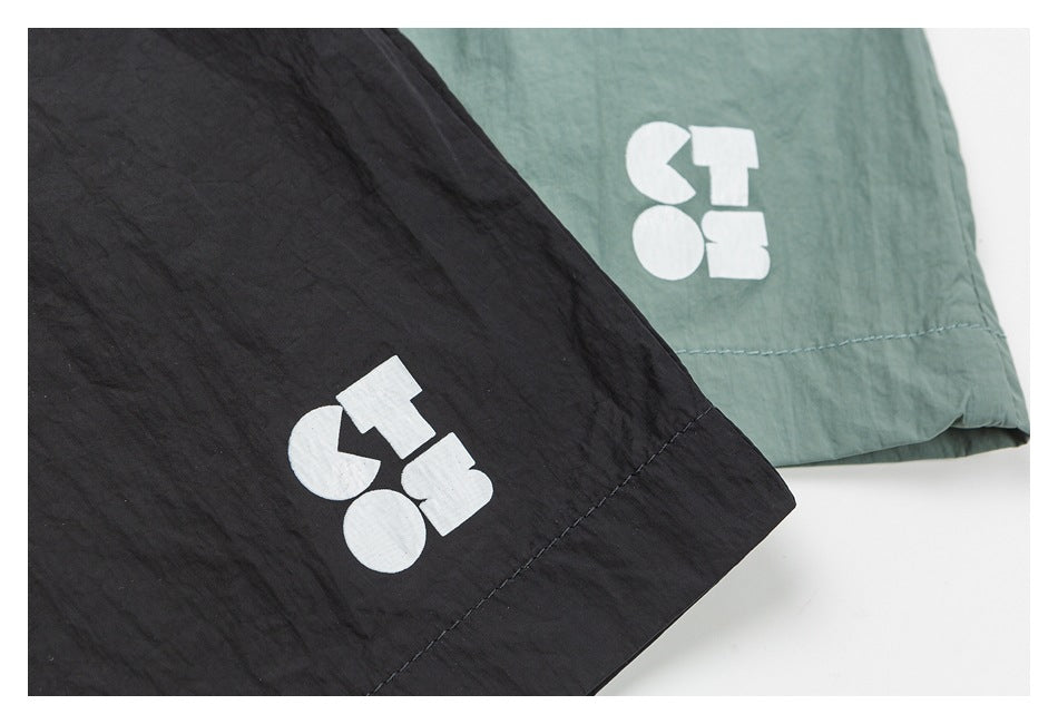 Close-up of black and sage green shorts hems with white geometric prints.