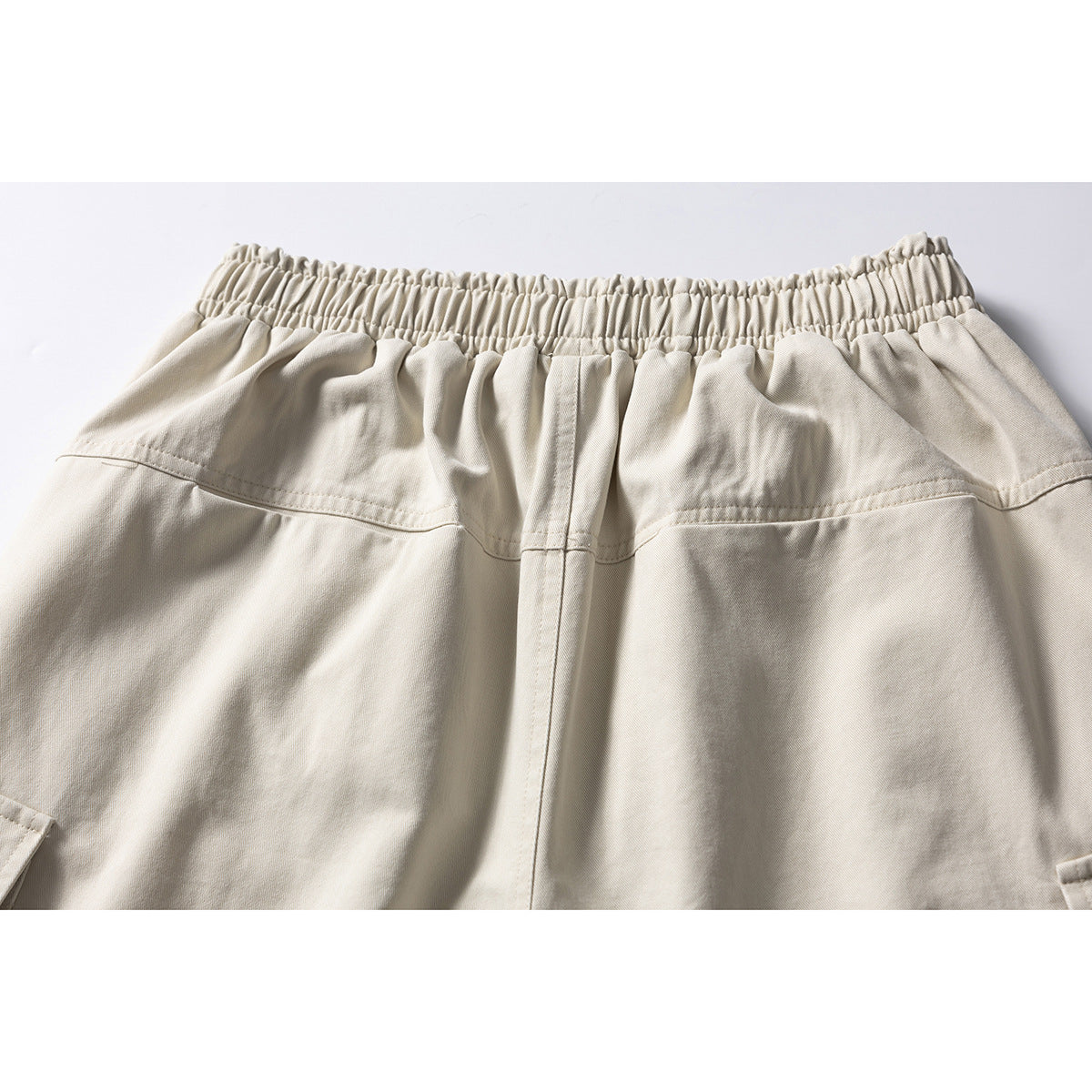 Close-up of the cream shorts’ gathered waistband and upper back seams.