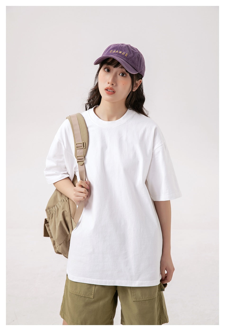 Closer front view of a model wearing an oversized plain white T-shirt and olive shorts.