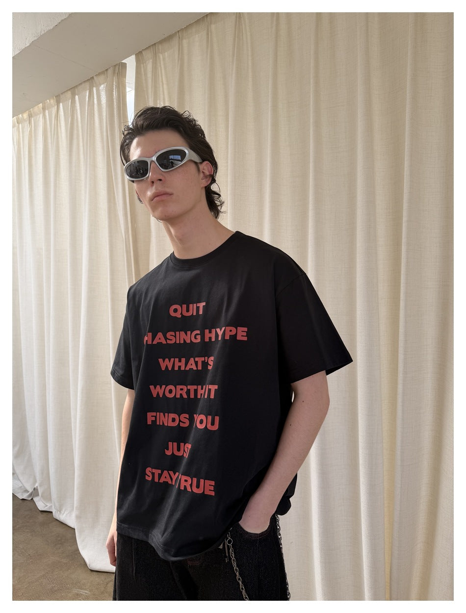 Closer view of a model wearing a black T-shirt with a red text graphic and silver sunglasses.