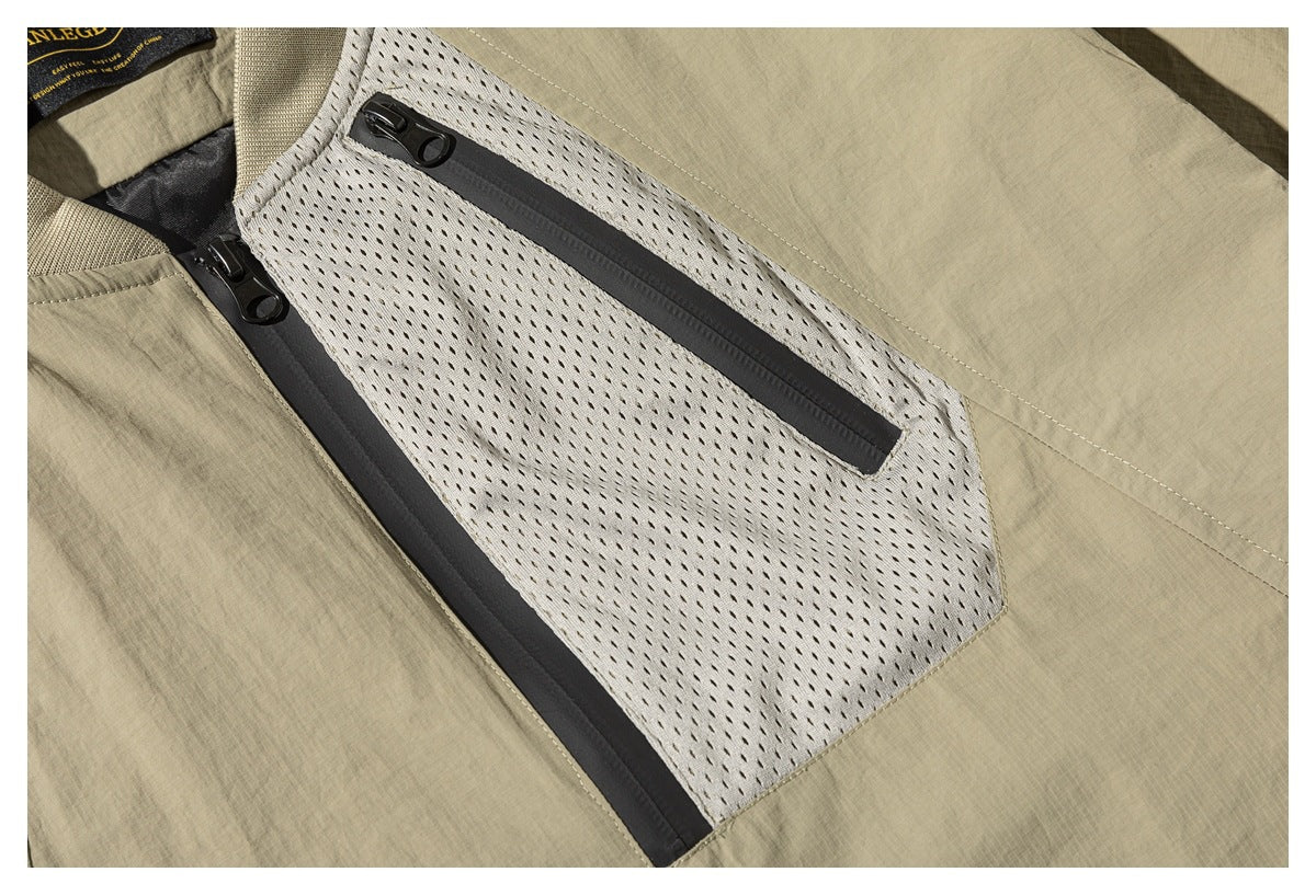 Close-up of a khaki jacket's perforated mesh chest panel and dark horizontal zip pocket.