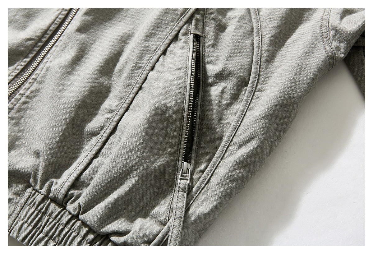Close-up of a gray-green jacket showing a metal zipper and a vertical zippered pocket.