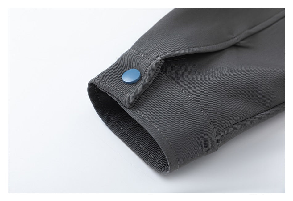 Close-up of a charcoal jacket cuff with a blue snap fastener.