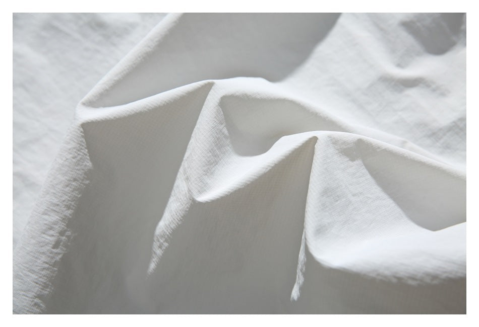 Close-up of pale gray woven fabric draped in soft folds.