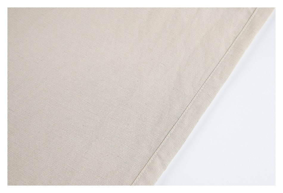 Close-up of beige trouser fabric with a straight stitched edge.