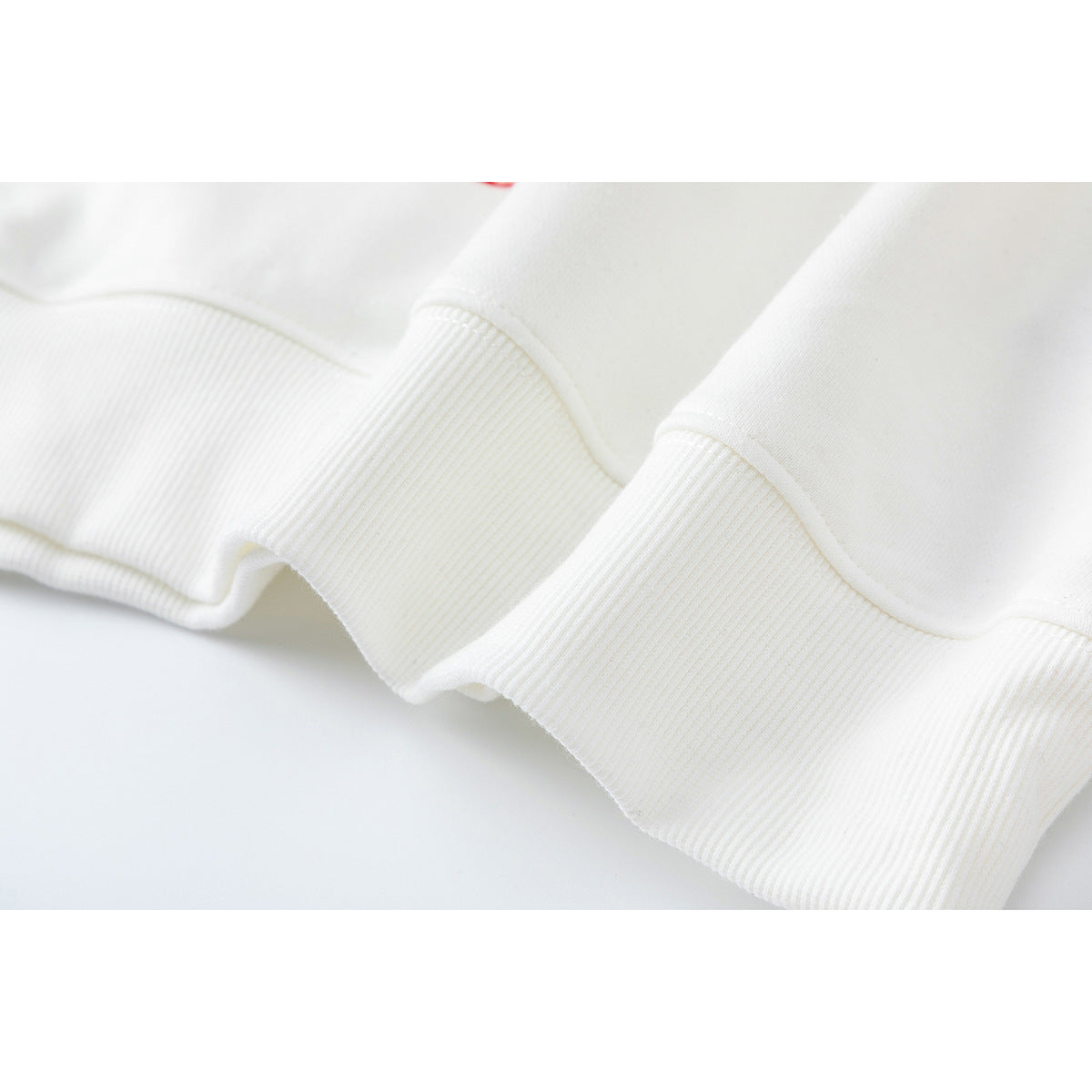 Close-up of a white sweatshirt's ribbed hem and stitched seams.