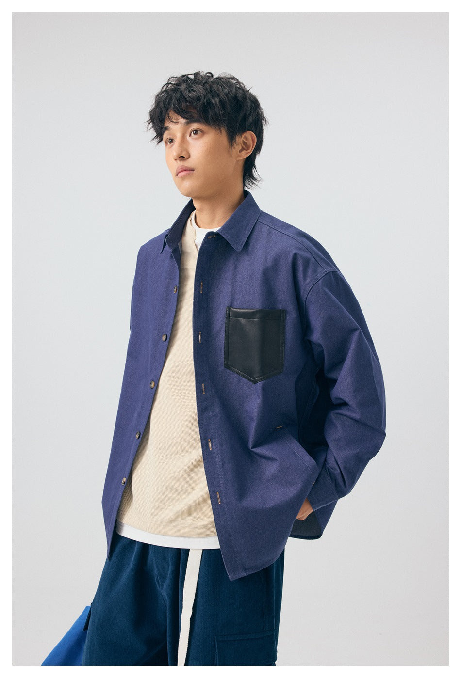 Model in a blue overshirt with a black chest pocket, shown at a three-quarter angle.