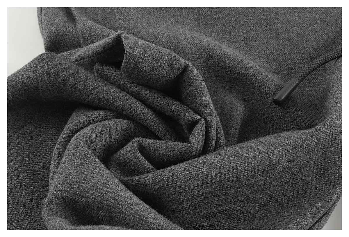 Close-up of dark gray textured garment fabric with a black drawstring end visible.