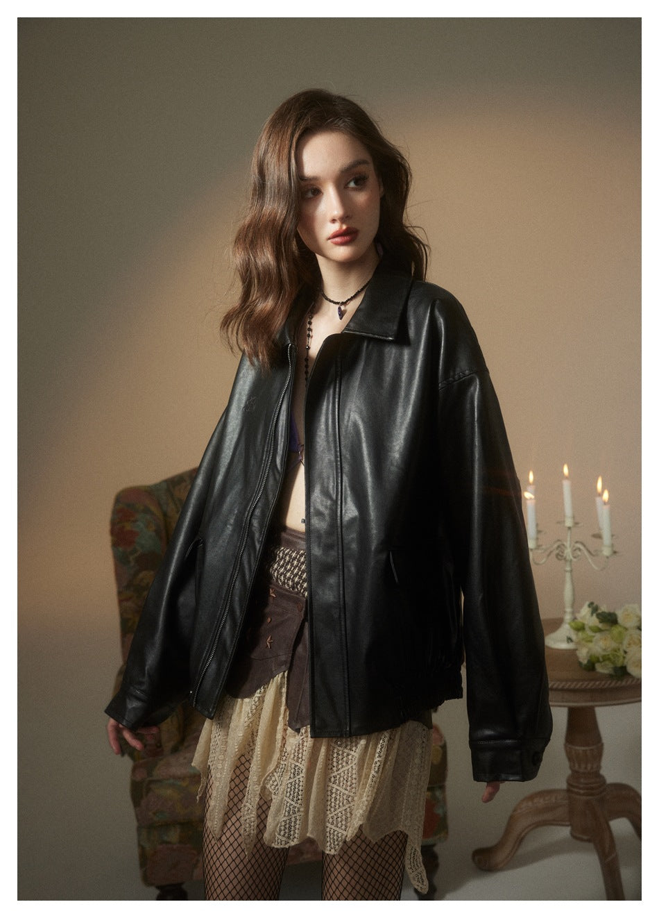 Closer view of a model wearing a glossy black oversized jacket with a pointed collar, zip front, and flap pockets.