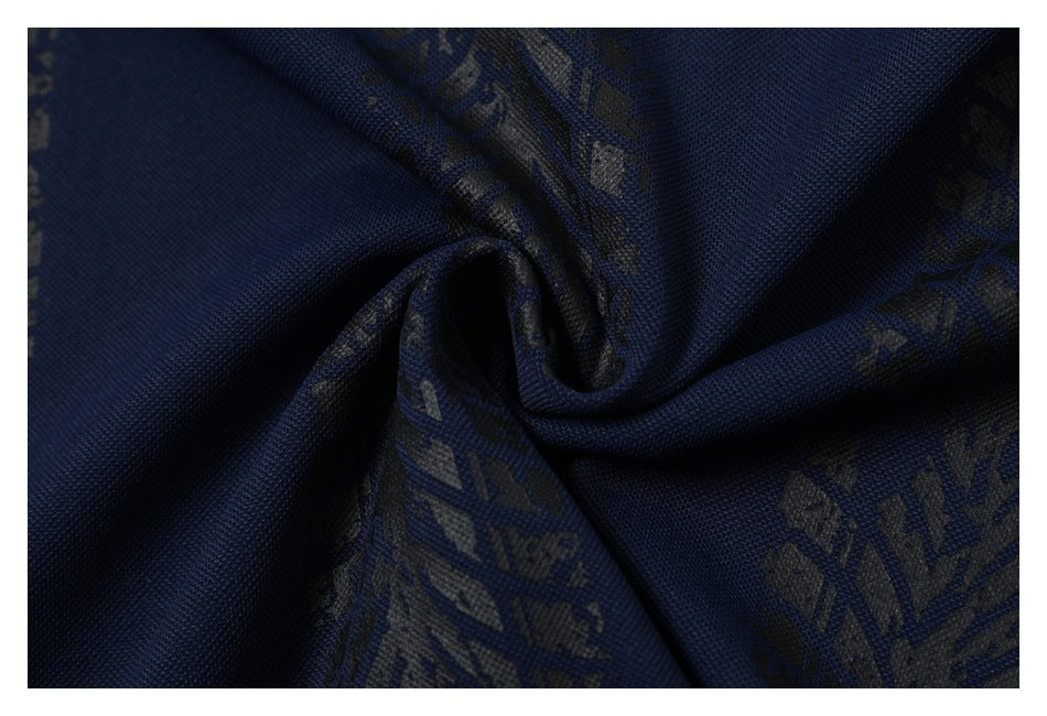 Close-up of navy fabric with dark abstract printed motifs gathered into a spiral fold.