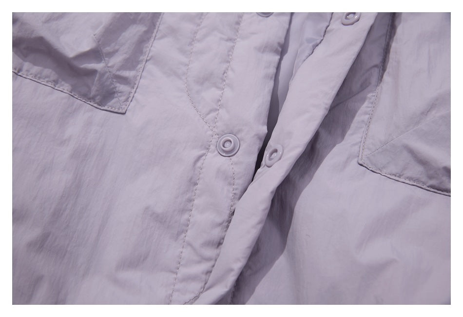 Close-up of a pale lavender garment front with matching snap buttons and patch pockets.