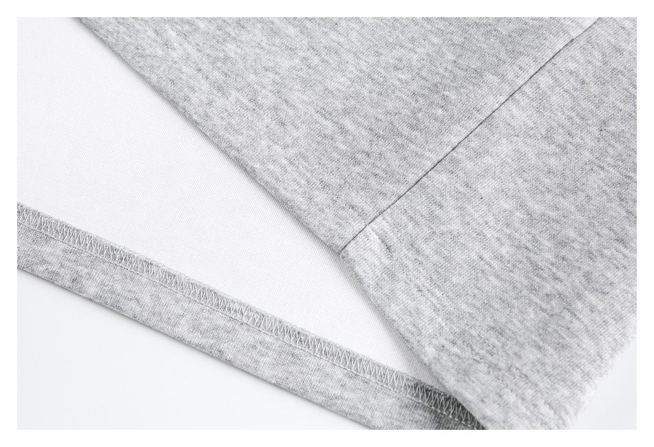Close-up of a light gray heather garment showing a stitched edge and white inner surface.