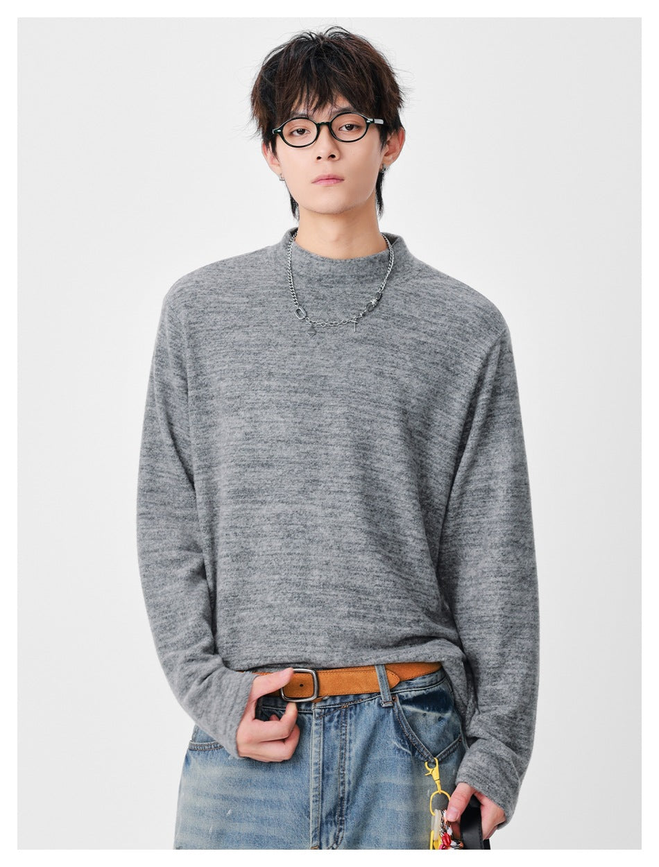 Front view of a model wearing a heather gray mock-neck long-sleeve top with a relaxed fit.