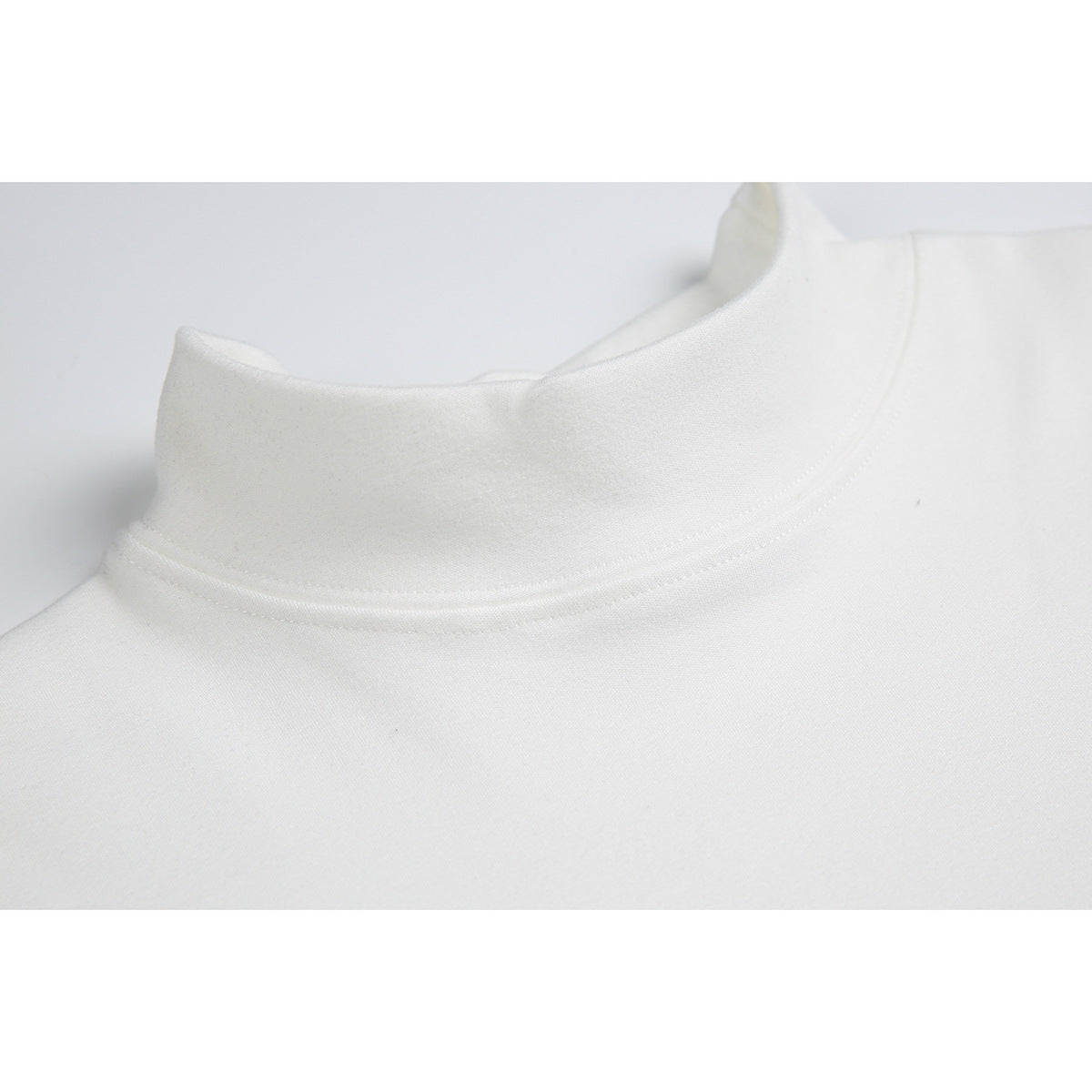 Close-up of the white shirt's raised mock neck and curved neckline stitching.