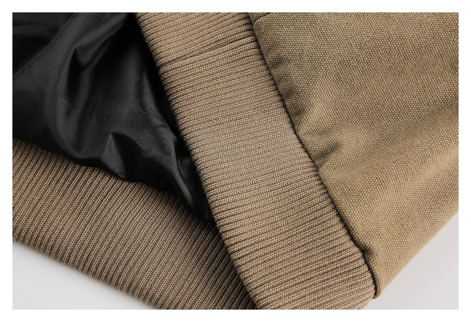 Close-up of tan woven garment fabric, ribbed knit trim, and black lining.