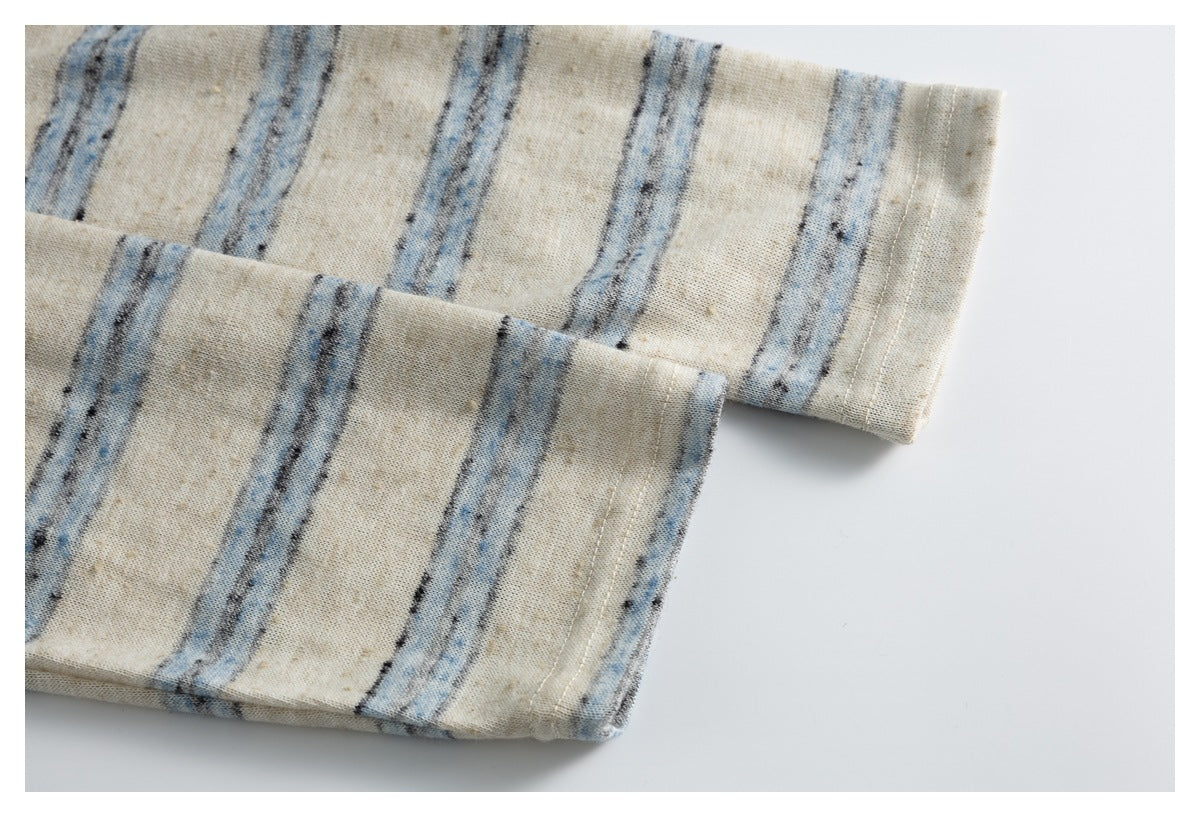 Two overlapping cream fabric edges with finished stitching and irregular blue and charcoal stripes.