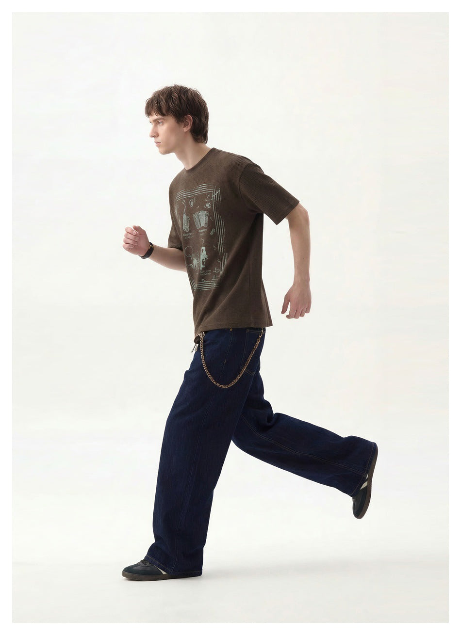 Side-view action pose showing a model in a dark brown graphic T-shirt and wide-leg dark blue jeans.