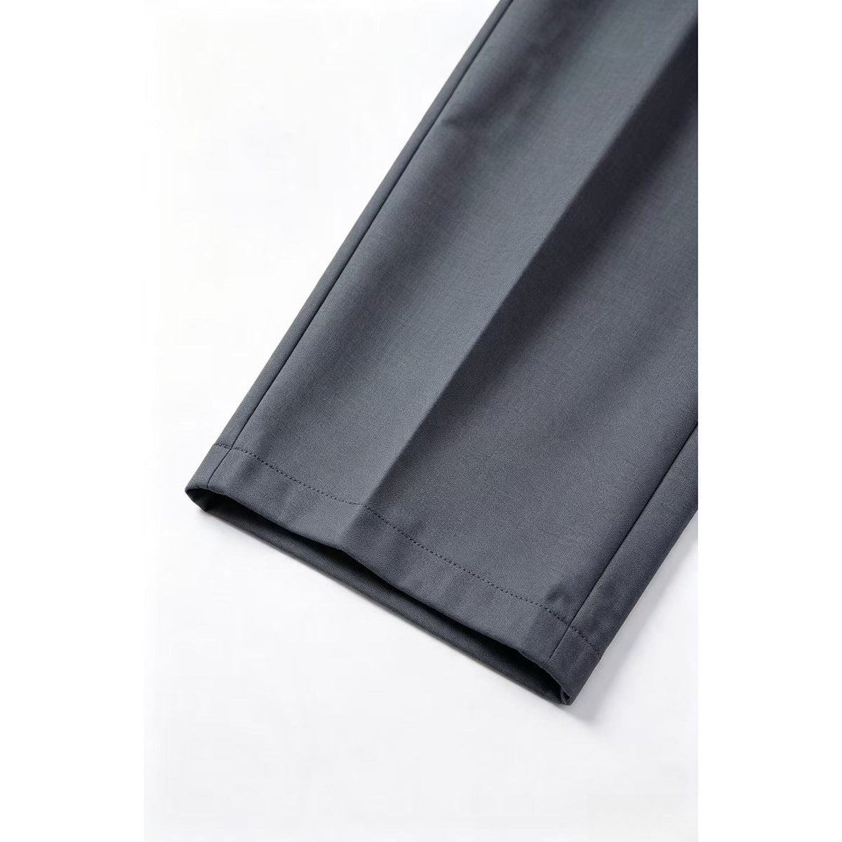 Close-up of a charcoal-gray trouser leg showing the straight hem and stitched edge.