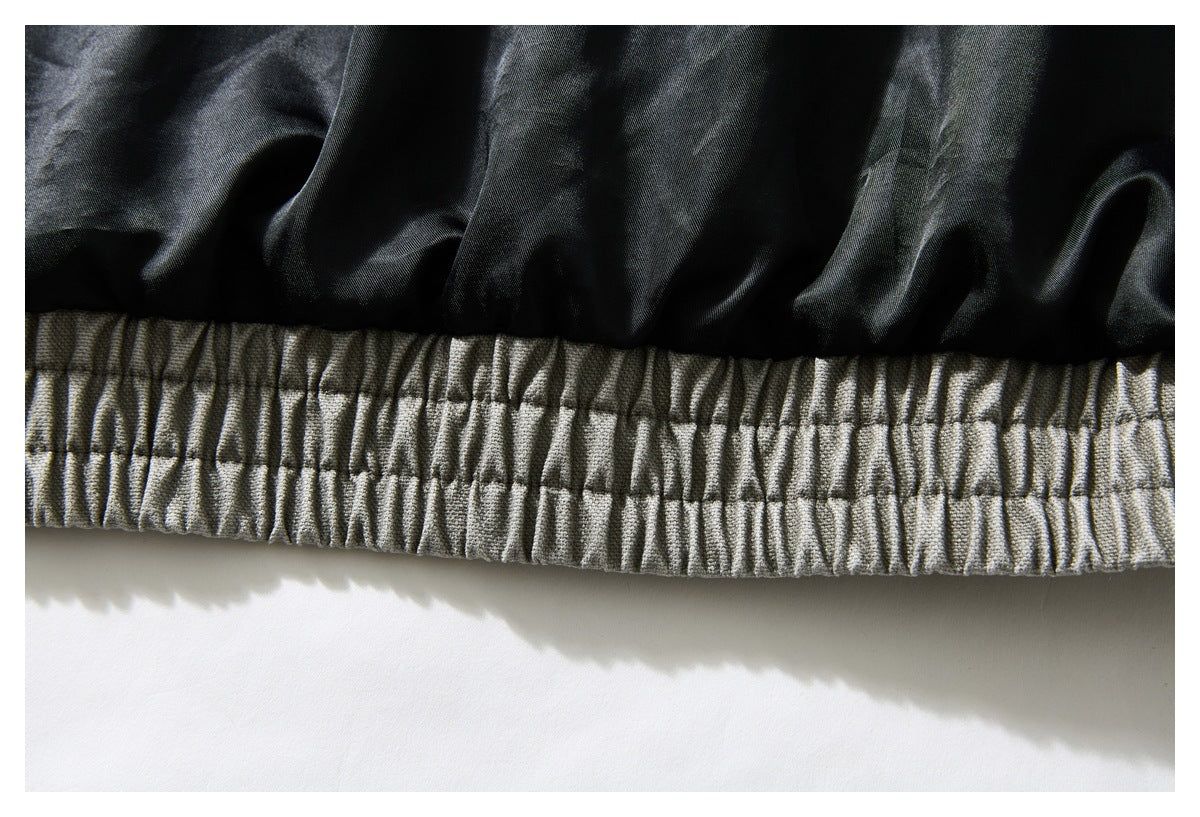 Close-up of a gathered gray-olive elastic waistband beside black lining.