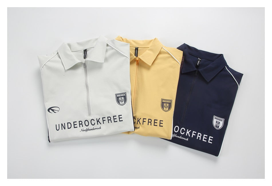 Three folded collared zip-neck tops in white, pale yellow, and navy, each with printed lettering and a shield emblem.