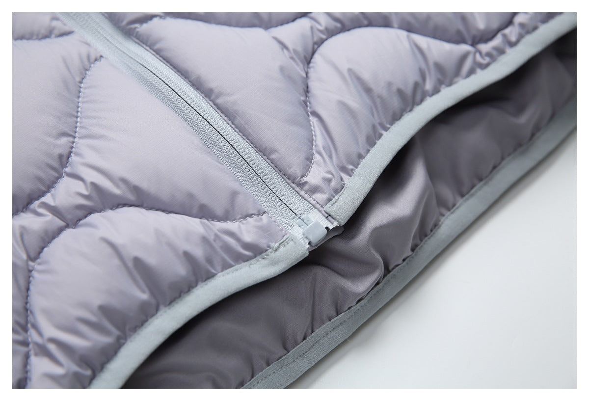 Close-up of a pale gray zipper and bound edge on a lavender quilted garment.